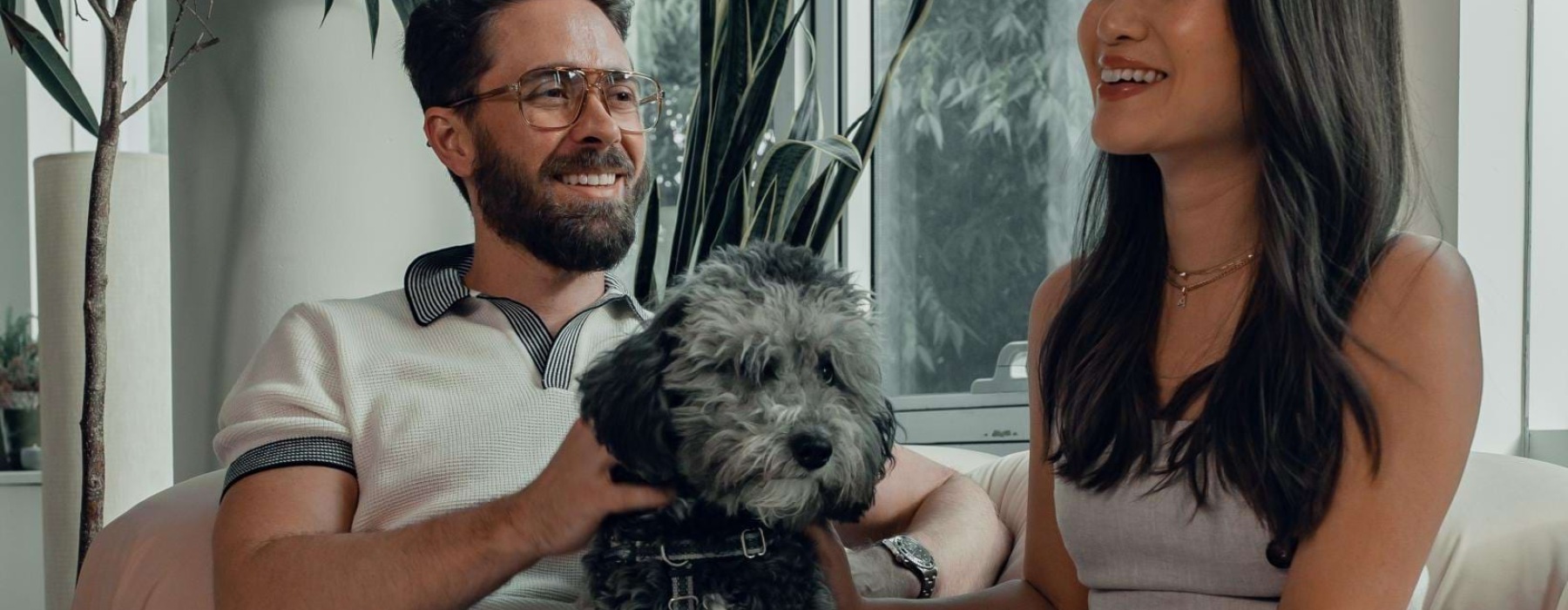 a man and woman sitting on a couch with a dog